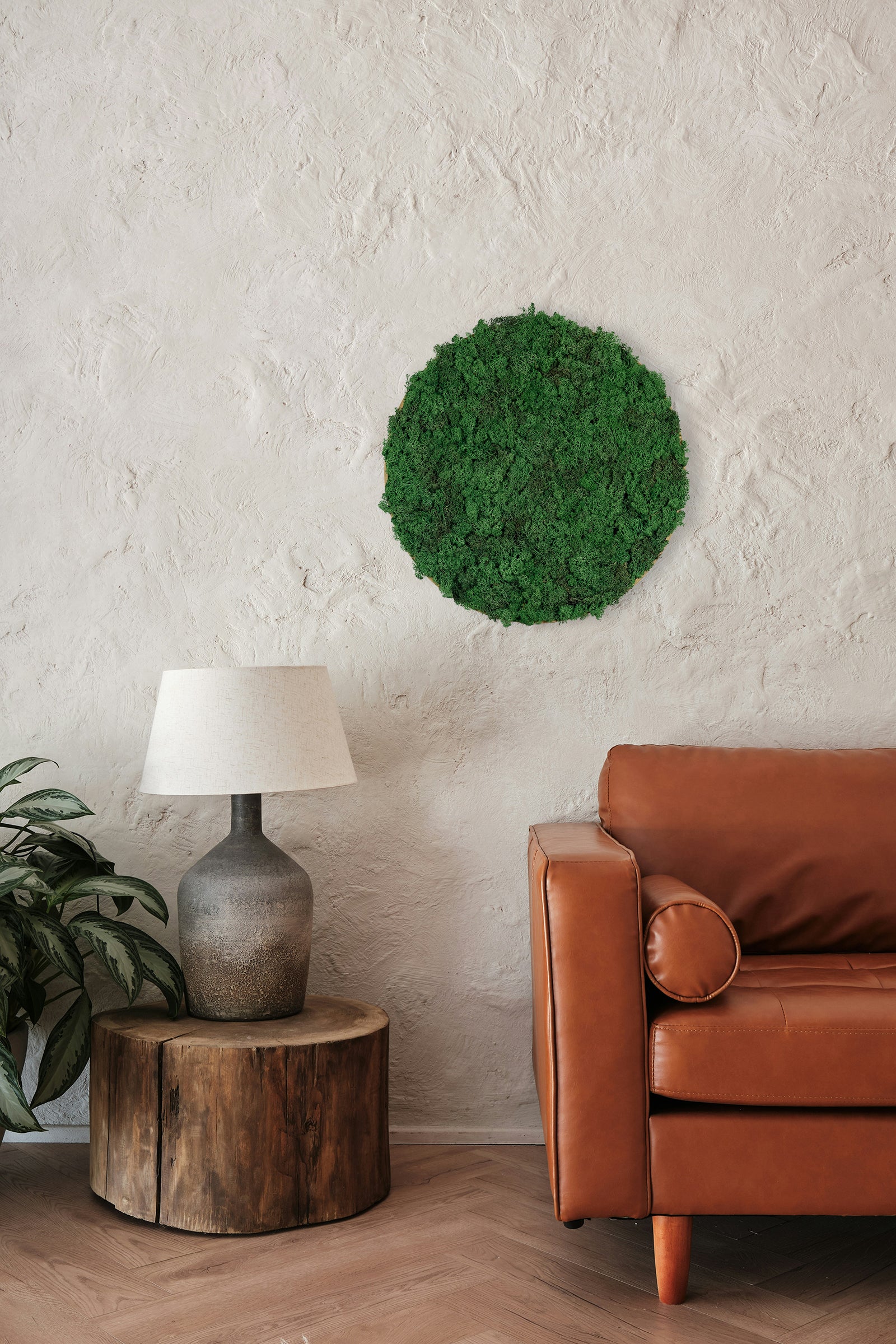 Rundt mosbillede med grønt mos i flere nuancer og sort kant. Moskunst skaber en behagelig akustik og en afslappet atmosfære. 